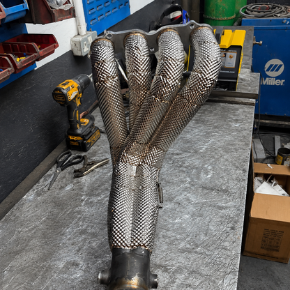 Four-branch exhaust manifold covered with a custom fabricated embossed stainless heat shield