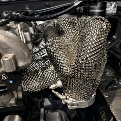Custom fabricated stainless exhaust heat shield installed around pipework in an mx-5 engine bay